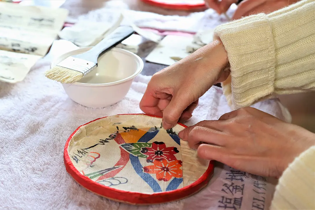 デザインを考えながら和紙や古布を貼って行く。